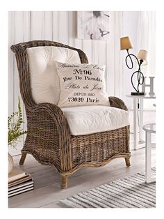 a wicker chair with pillows on it in front of a white wall and floor