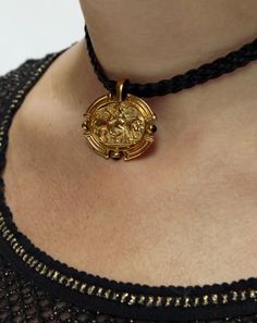 "Inspired by ancient Roman jewelry, this golden pendant sits on a braided cord, emblazoned with a mythological vignette, featuring a winged angel and an oxen. From the emblem to the shield-like shape of the pendant, it has an Etruscan feel. It sits on a vegan leather braided cord, which has a magnetic closure in the back. Pendant measures about 31 mm wide x 28 mm high, and the cord is 13.5\" long. ** The Vintage Dolce & Gabbana Metallic Knit Top pictured is also available: verybreezy.com/product Mythological Medallion Jewelry In Gold, Gold Mythological Jewelry With Coin Pendant, Gold Mythological Coin Pendant Jewelry, Mythological Style Gold Coin Pendant Jewelry, Fae Jewelry, Modest Jewelry, Etruscan Jewelry, Leather Braiding, Ancient Roman Jewelry