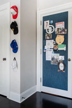 two white doors with hats on them in front of a wall mounted baseball cap rack