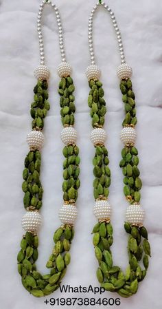 three necklaces with pearls and green beads on white cloth background, one is made out of