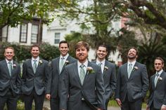 a group of men standing next to each other wearing suits and ties with trees in the background