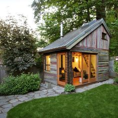 a small wooden shed with windows on the roof and doors open in front of it