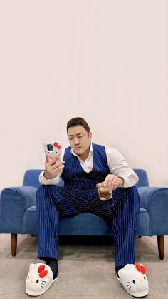 a man sitting on top of a blue couch holding a remote control in his hand