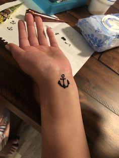 a person's hand with a small tattoo on their left wrist and an anchor in the middle