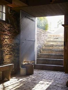 an open door leading to a stone building with stairs and brick flooring on either side