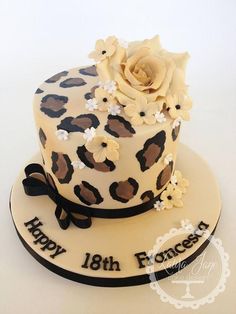 a leopard print cake with a white rose on top and happy 18th birthday written on the side