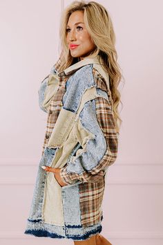 a woman standing in front of a pink wall wearing a plaid jacket and jeans pants