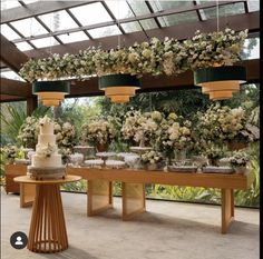 a table topped with lots of white flowers next to a wall covered in greenery