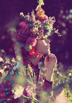 a woman with flowers in her hair is sitting in the grass and looking at something