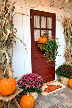 some pumpkins and flowers are on the front porch