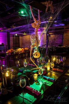 a skeleton is suspended from the ceiling above a table with wine glasses and candles on it