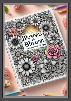 an adult coloring book with flowers on the cover and colored pencils next to it