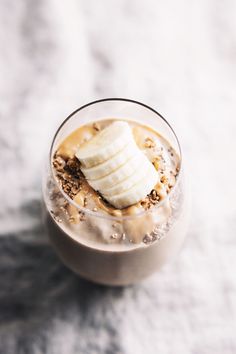 a glass filled with ice cream and bananas on top of a white tablecloth covered surface