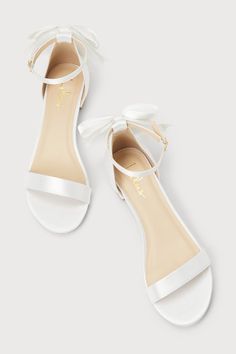 Make a sweet statement at your next soiree with the Lulus Charmane White Satin Bow Ankle Strap Sandals! Sleek satin shapes these adorable shoes that have a slender toe strap and a matching ankle strap that secures with a shiny gold buckle. A cute, oversized bow adorns the structured heel cup atop a low block heel that lends the perfect pep to your step. 1. 25" wrapped block heel. Cushioned insole. Felted rubber sole has nonskid markings. Man made materials. Imported. Lulus | Charmane White Satin Spring Wedding Shoes With Satin And Round Toe, Satin Round Toe Wedding Shoes For Spring, Spring Wedding Satin Shoes With Round Toe, Spring Event Heels With Satin Bow, Summer Evening Heels With Satin Bow, Spring Evening Wedding Shoes With Satin Bow, Event Ankle Strap Heels With Satin Bow, Chic Summer Wedding Guest Shoes, High Heel With Satin Bow For Summer