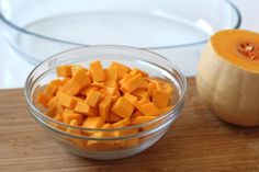 a bowl filled with cut up pumpkins next to a glass bowl full of diced squash