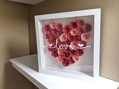 a heart made out of rolled paper with the word love written on it in white frame