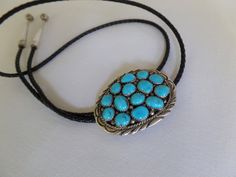 "This handsome bolo tie features turquoise set in sterling silver, by artist Marie B.  Clasp is 2\" long and 1.5\" wide.  The silver capped ends of the leather cord are 2\" long.  Marked STERLING." Elegant Blue Concho Jewelry, Elegant Blue Jewelry With Concho Detail, Southwestern Blue Bolo Tie For Gift, Southwestern Blue Bolo Ties As A Gift, Blue Turquoise Concho Necklace As A Gift, Blue Handmade Bolo Tie Gift, Adjustable Southwestern Blue Bolo Tie, Adjustable Blue Southwestern Bolo Tie, Handmade Turquoise Bolo Tie As A Gift