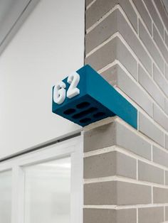 the number 32 is mounted to the side of a brick building with blue paint on it