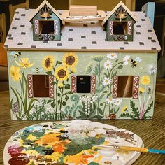 a doll house painted with sunflowers and paintbrush