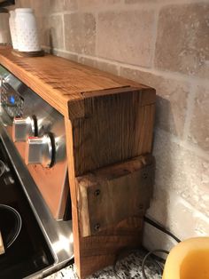 a stove top oven sitting inside of a kitchen next to a wooden shelf above it