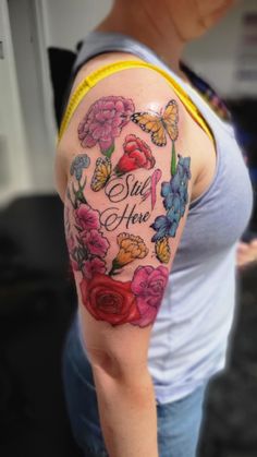 a woman's arm with flowers and butterflies on it, she says stay here