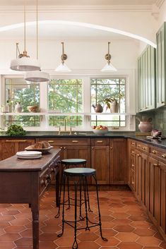 a kitchen with two stools in front of the counter and three lights hanging from the ceiling