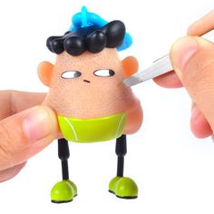 a person holding a small toy in their hand with a knife stuck to it's face