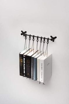 three books are hanging on the wall next to an open book rack with five different books