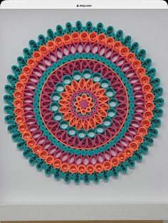 an art work made with crochet and yarn on a white surface in the shape of a circle