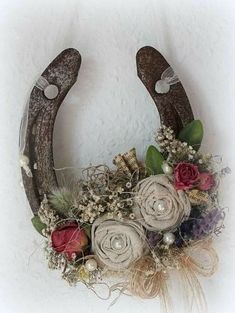 an antler decorated with flowers and feathers is hanging on the wall in front of a white wall