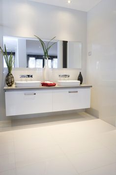 a bathroom with two sinks, mirrors and plants in vases on the counter top