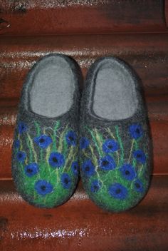 a pair of slippers with blue flowers painted on them sitting on a wooden step