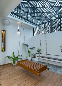 a wooden swing hanging from the ceiling in a room with white walls and wood flooring