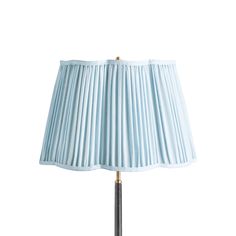 a lamp with a blue shade on top of it and a gold metal pole in the middle