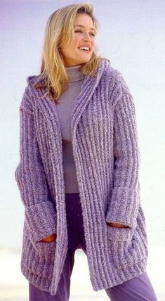 a woman is smiling while wearing a purple cardigan sweater and purple pants with her hands in her pockets