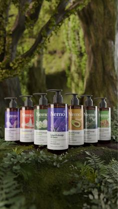 nine bottles of hand sanitizers are lined up in front of a tree with green leaves