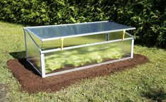 a small greenhouse in the middle of a field with grass and dirt on the ground