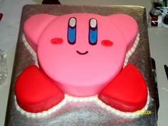 a pink cake with red hearts and eyes on it's face is sitting on a table