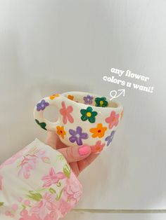 a hand holding a cup with flowers painted on it and the words, any flower colors are want