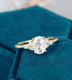 an engagement ring with three stones on it sitting on top of a blue velvet cloth