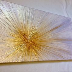 an abstract piece of art is displayed on a white tablecloth with gold foiling