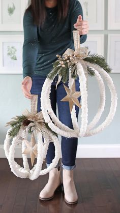 a woman holding two christmas ornaments in her hands