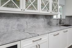 a kitchen with marble counter tops and white cabinets