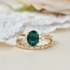 a close up of a ring with a green stone on the side and white diamonds around it