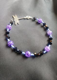 Purple glass bead bracelet with black crystal sparkling beads. Be ready for Halloween with this classy accessory. The bracelet in photo is 8 to 9  inches long with dragonfly extension (can be made to order according to wrist size/circumference). Please feel free to message me! A purple dragonfly represents spiritual growth and awareness, inner knowledge, and a higher perspective. Purple dragonflies are also associated with the Third Eye chakra. Gift: Great gift for birthdays, anniversaries, or a Purple Dragonfly, Higher Perspective, Halloween Purple, Glass Bead Bracelet, Purple Sparkle, Third Eye Chakra, Glass Beaded Bracelets, Purple Glass, Black Crystals