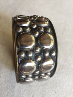 "Boho Metal Bangle Bracelet, Silver Bubbles of varying sizes with black undertones. Inside is a bronze gold color. Measures about 9.25\" around and 1.5\" wide. Inside is a tag that says CI, No. 325, and if anyone knows what that means please tell me! Also, please take a look at my storefront at: https://www.etsy.com/shop/FabFinds42?ref=seller-platform-mcnav I have a wide selection of one-of-a-kind items, from clothing and toys to home decor and gift items, and I add new things almost every day!" Bohemian Round Bracelets For Collectors, Bohemian Round Collectible Bracelets, Unique Adjustable Nickel-free Bangle, Adjustable Nickel-free Bangle, Handmade Adjustable Sterling Silver Bracelet Collectible, Unique Nickel-free Round Cuff Bracelet, Vintage Adjustable Stackable Cuff Bracelet, Adjustable Unique Style Nickel Free Bangle, Unique Nickel-free Cuff Bracelet