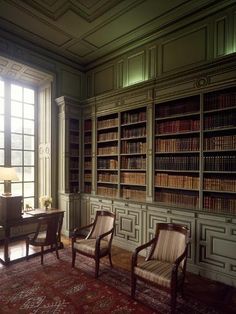 an old library with two chairs and a desk in front of a large bookcase