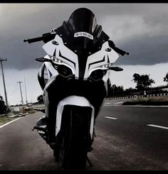 a white and black motorcycle parked on the side of the road with dark clouds in the background