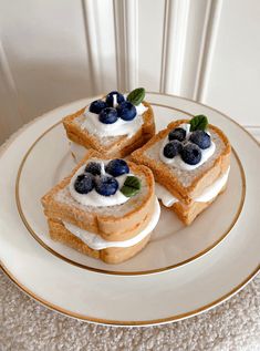 three pieces of toast with blueberries and whipped cream on them sitting on a plate