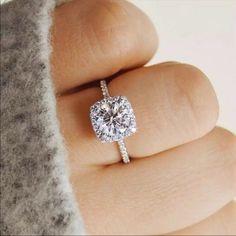 a woman's hand with a diamond ring on top of her finger and an engagement band